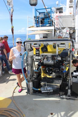 Heather Bracken-Grissom stands next to a remote operated vehicle aboard the Pelican to collect bioluminescent organisms and explore the deep sea.