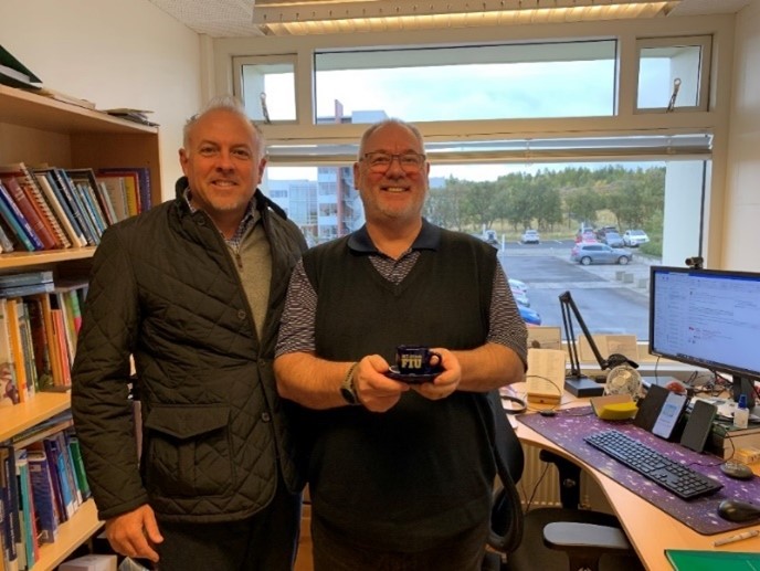 Rob Guerette (left) with the Chief of Icelandic Police Training presenting an FIU cafecito cup