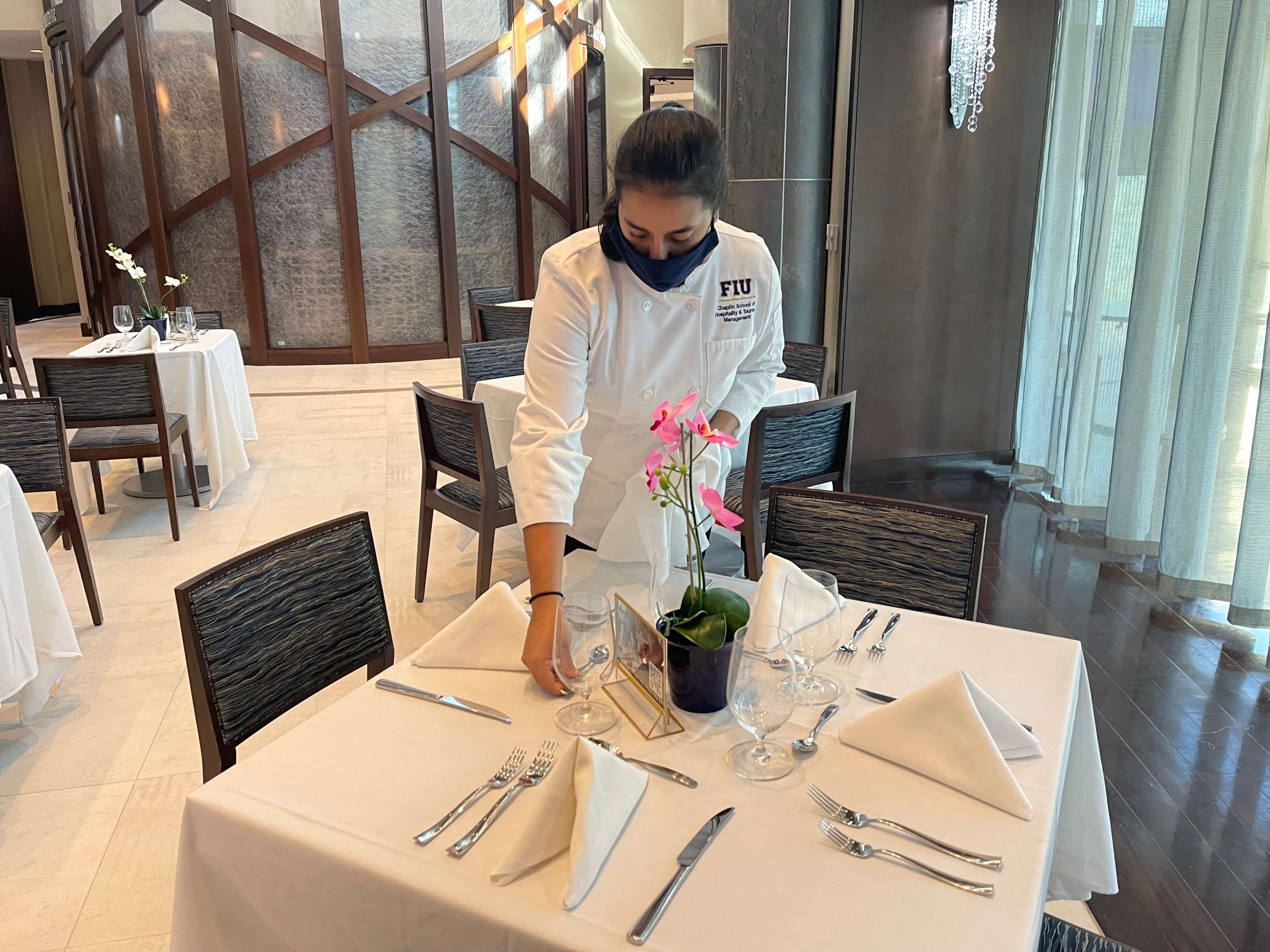 Hospitality student Maria Alonso, acting manager for the week, sets tables and makes sure silverware is polished.
