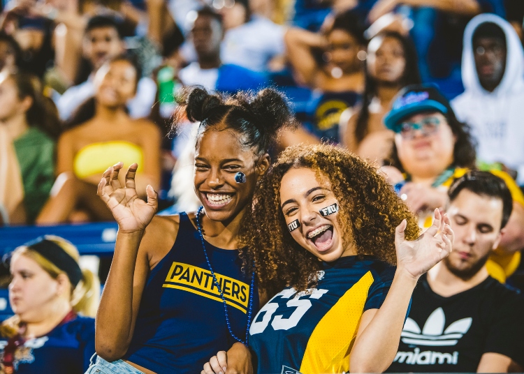 Two students put their paws up at a football home game.