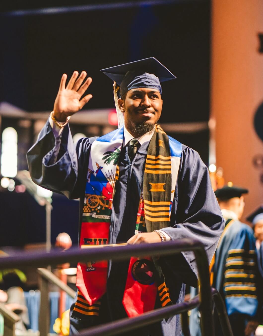 Graduate with Haiti stole waving on stage