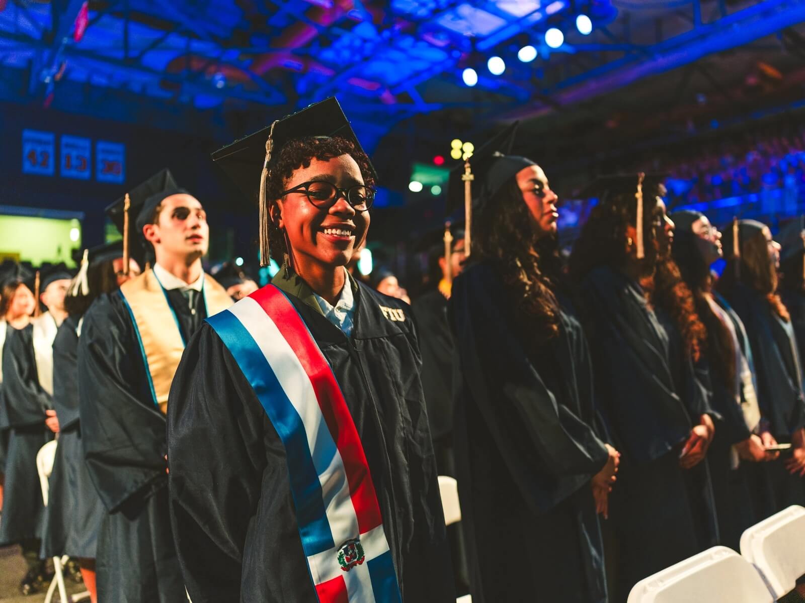 Graduate with Dominican Republic stole smiling in crowd