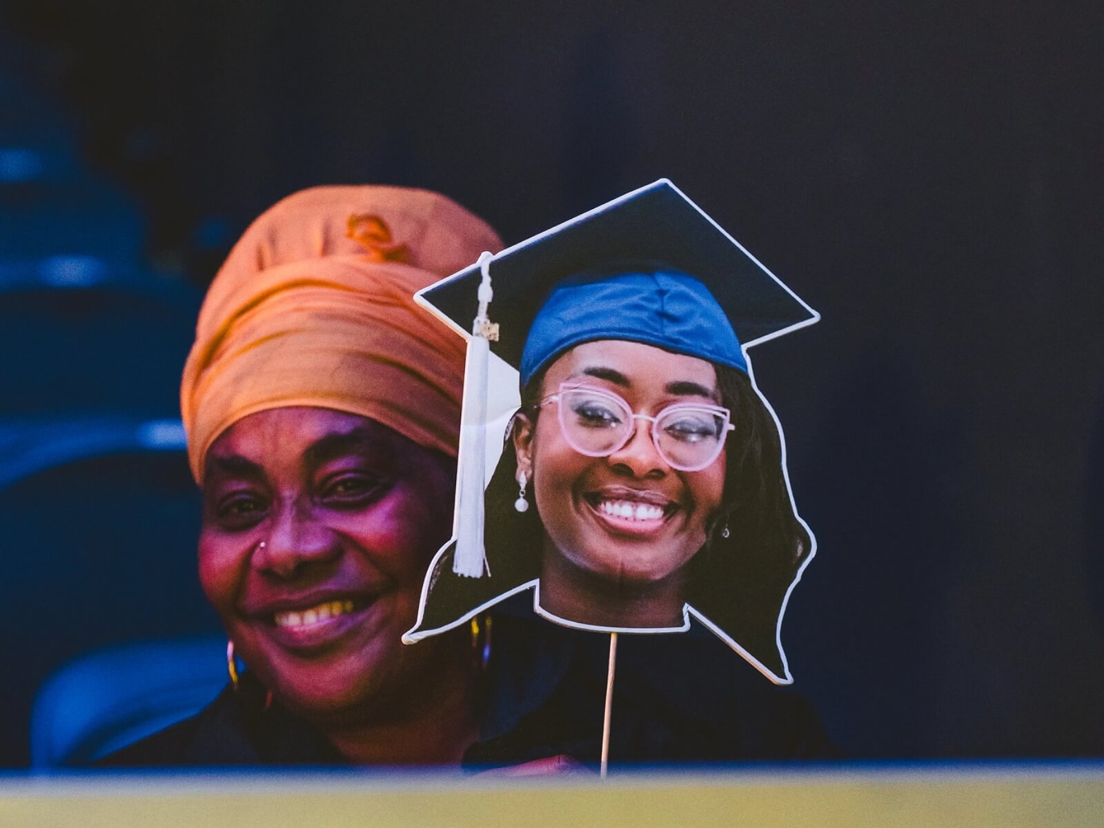 Woman in audience holding graduate big head cutout