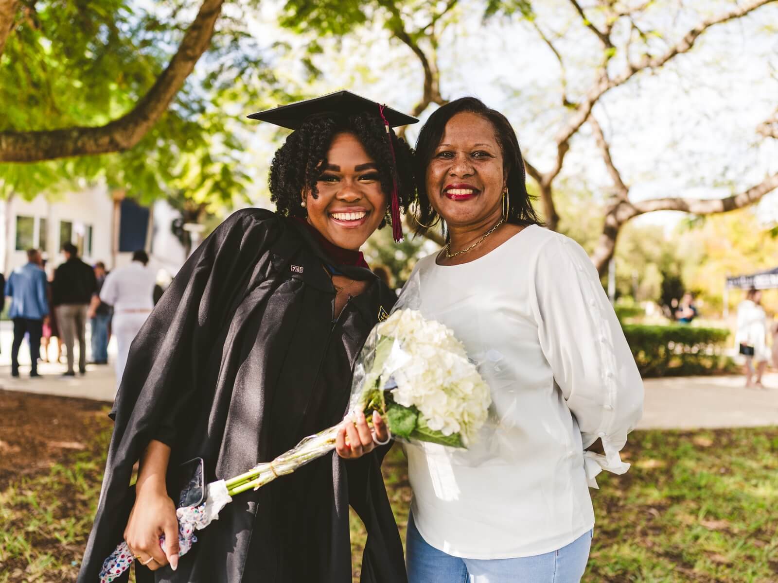 Graduate holding flowers and posing with relative