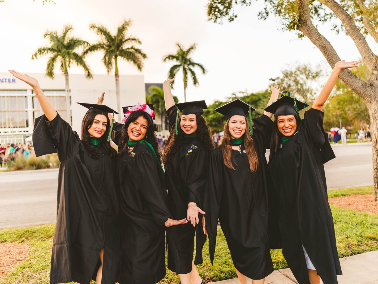 Graduates outside throwing arms up in celebration