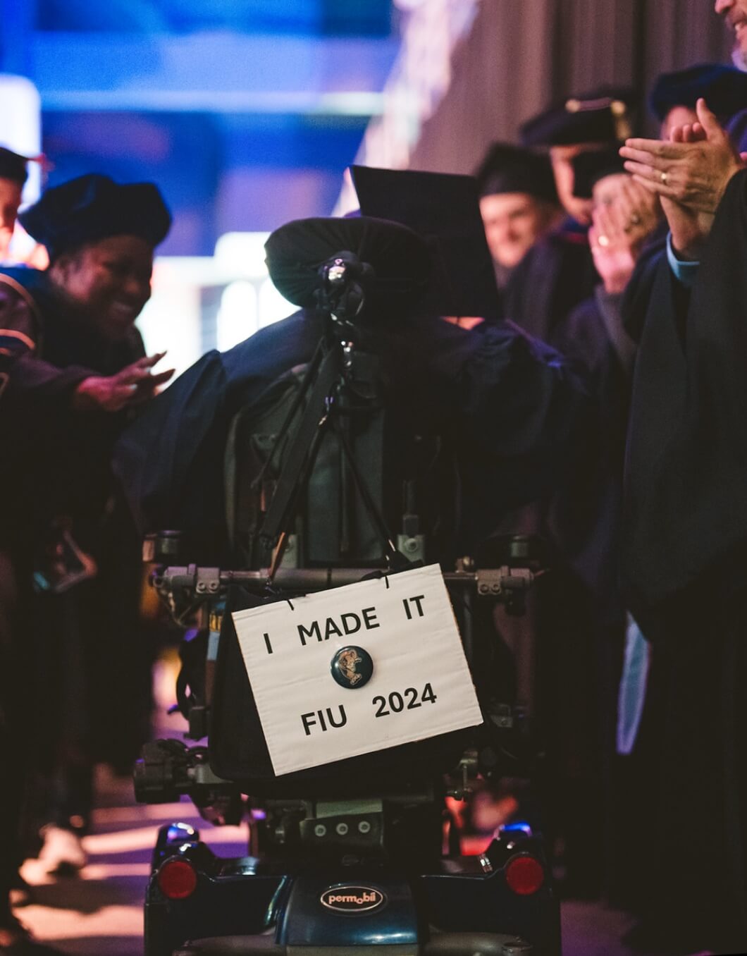 Graduate in electric wheelchair going on stage