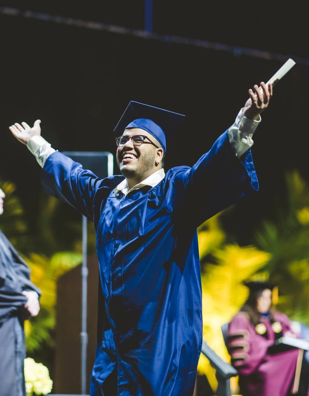 Graduate holding arms out and cheering