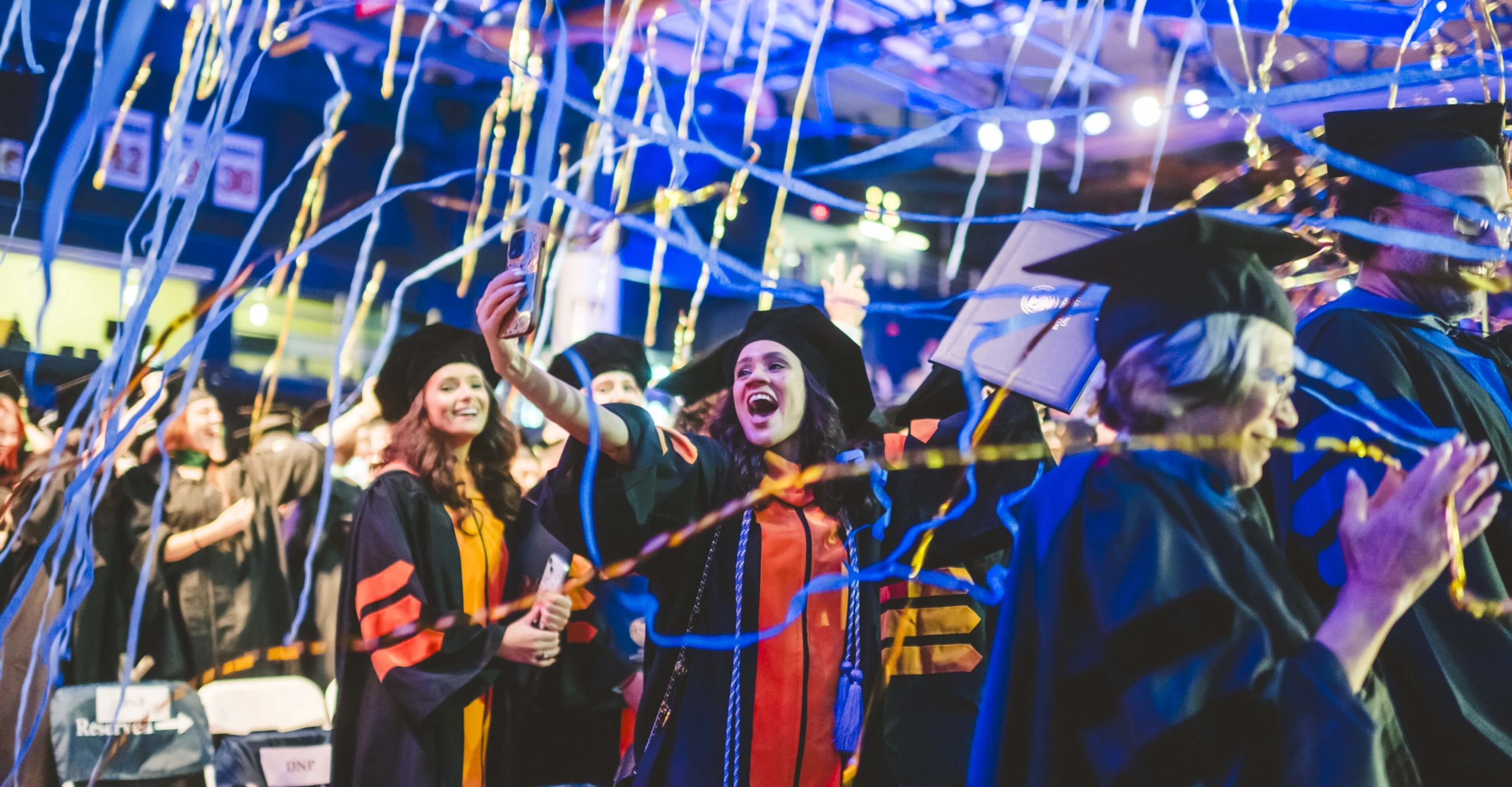 Doctoral graduate taking a selfie as confetti drops down