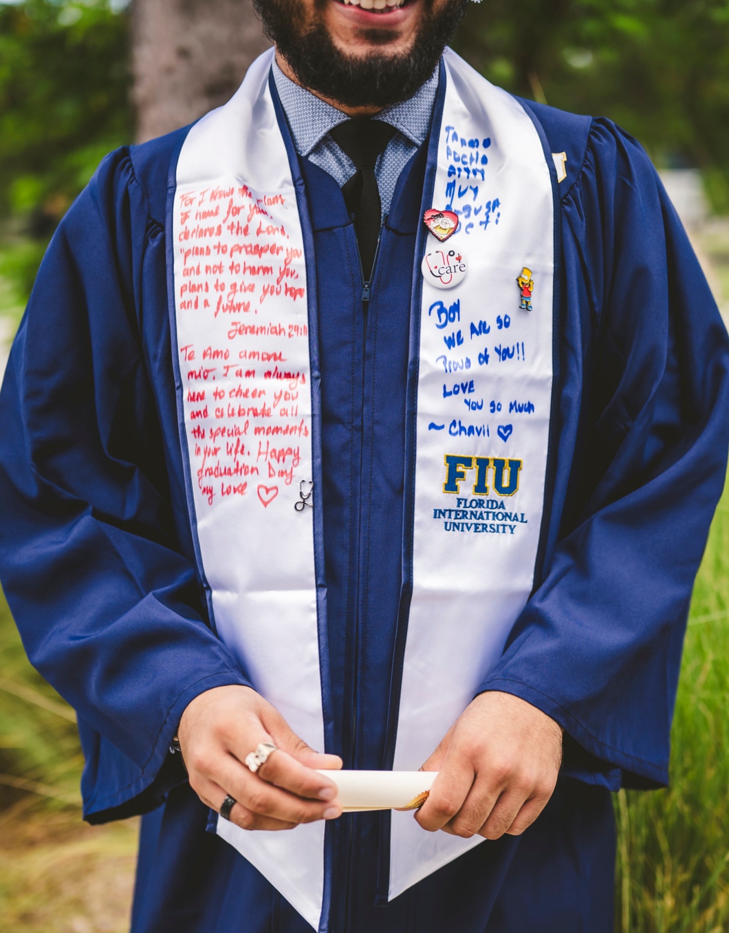 Graduate showing his commencement stole, which is signed by family and friends