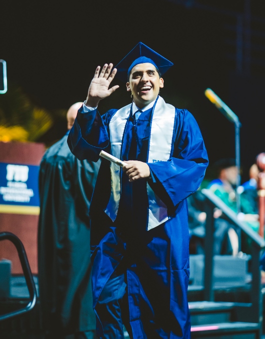 Graduate waving with his diploma