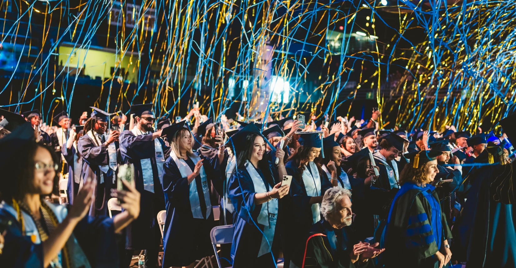 Graduates celebrating as confetti falls from the air
