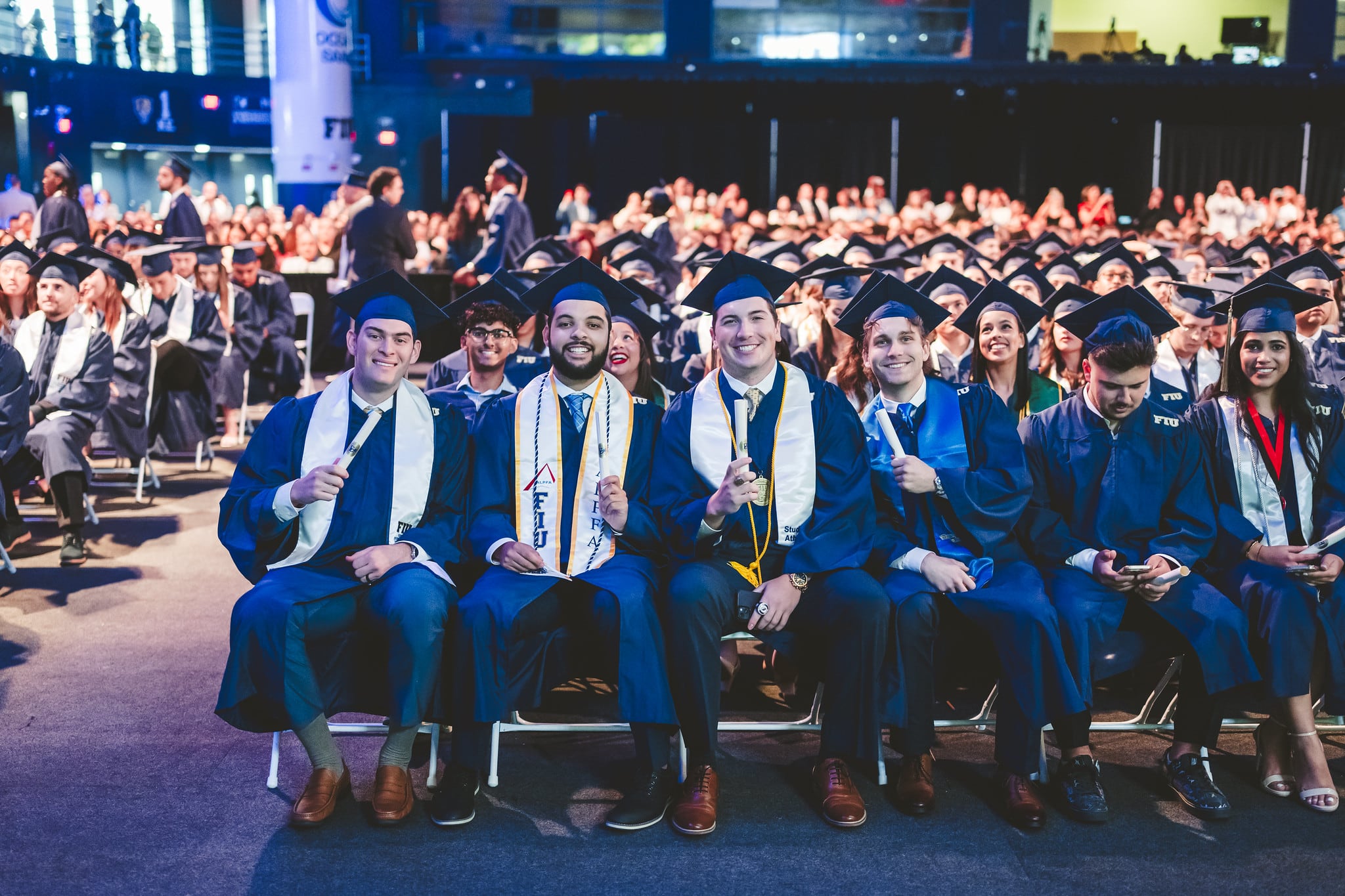 Graduates smiling in seats during commencement