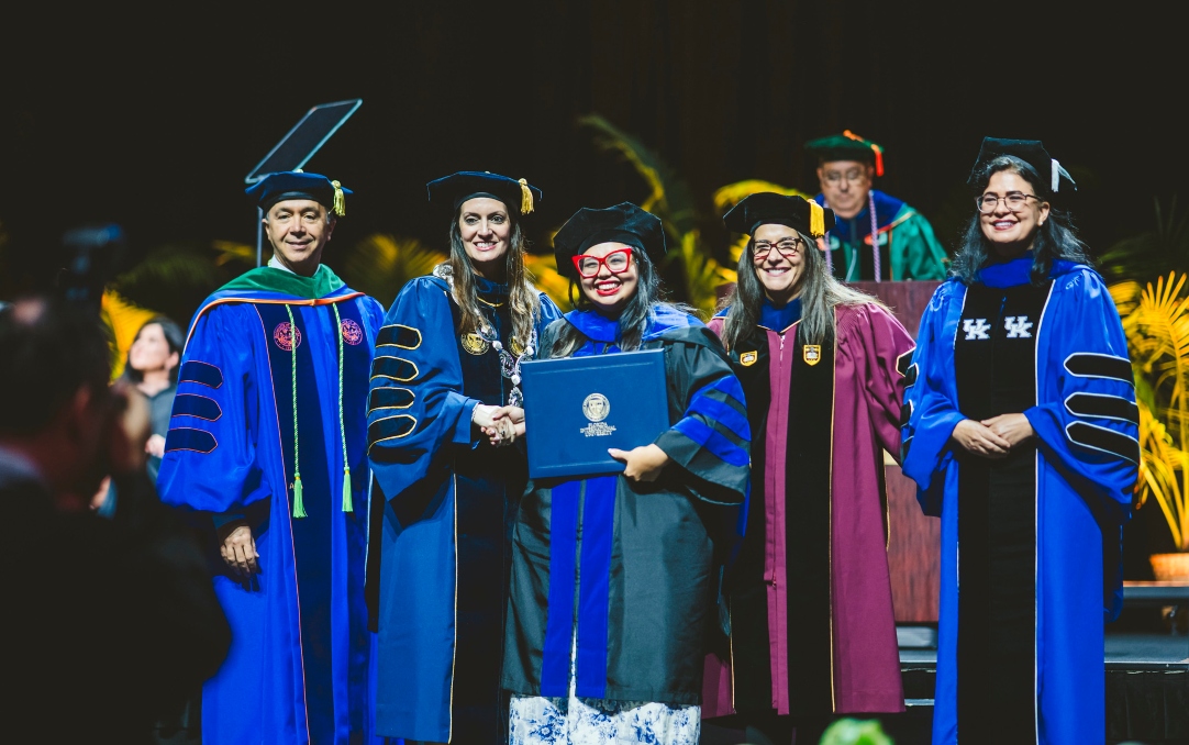 Graduate student posing with diploma and university leaders