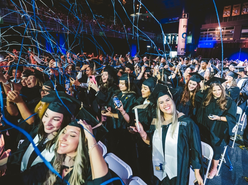 Crowd of graduates cheering as confetti drops