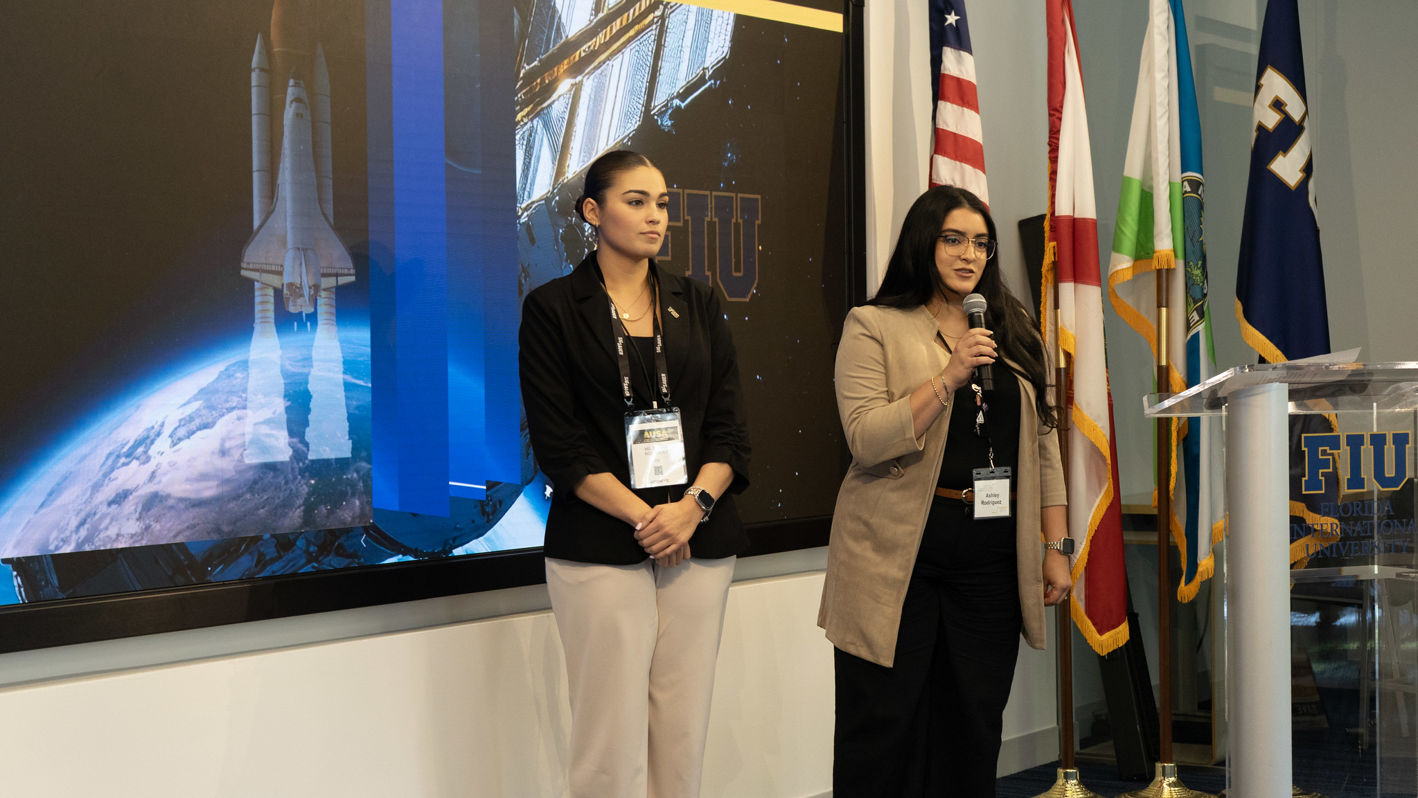 Rodriguez (holding microphone) and fellow student Sophia Rodriguez presenting during a small hackathon the students participated in during the trip.