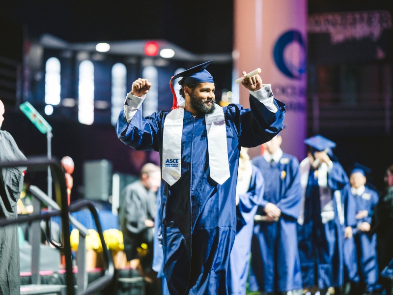 Graduate celebrating as he walks across the commencement stage