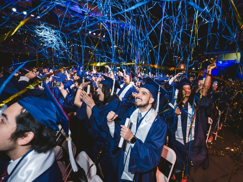 Crowd of graduates cheering as confetti drops