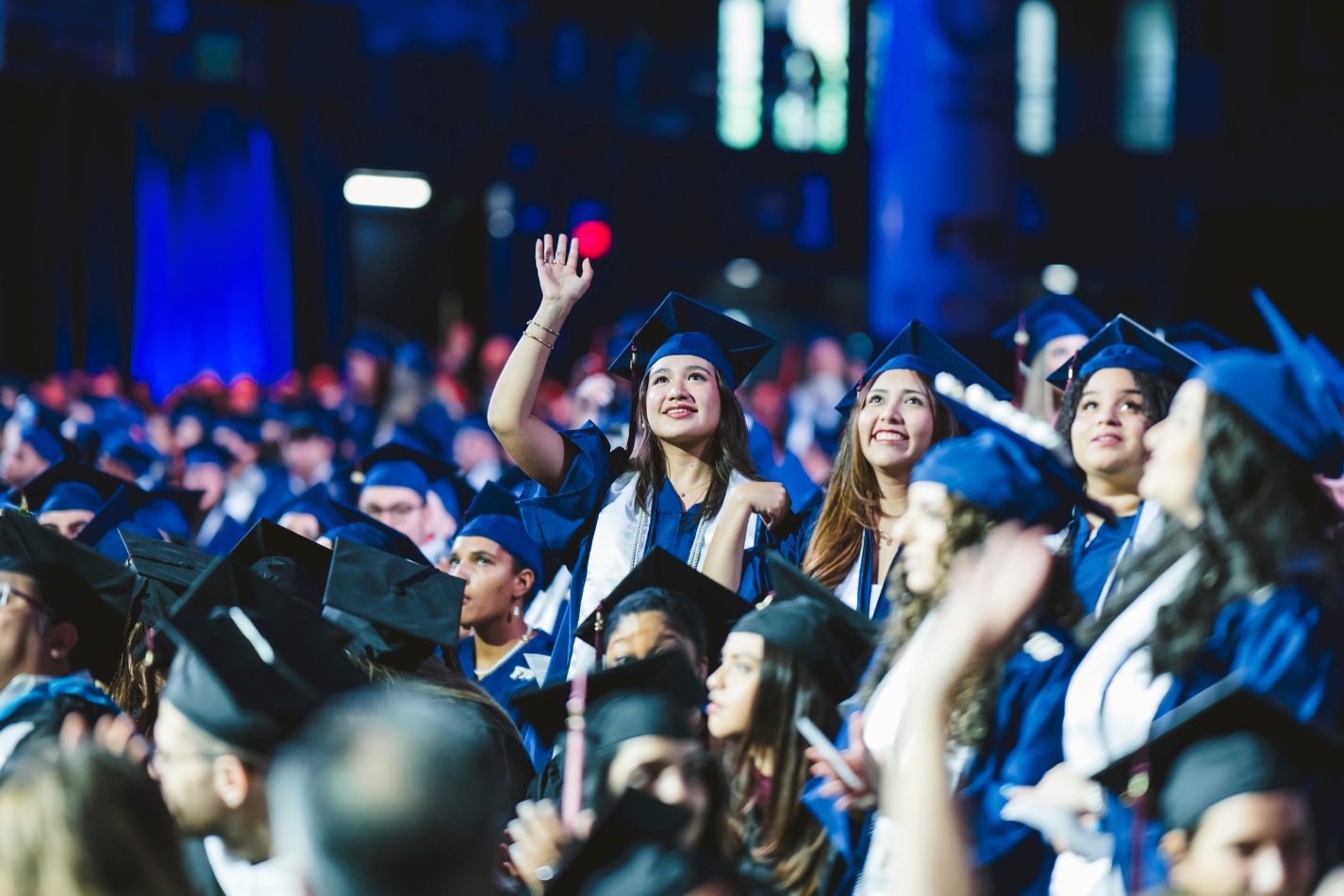 Student in cap and gown during commencement waving