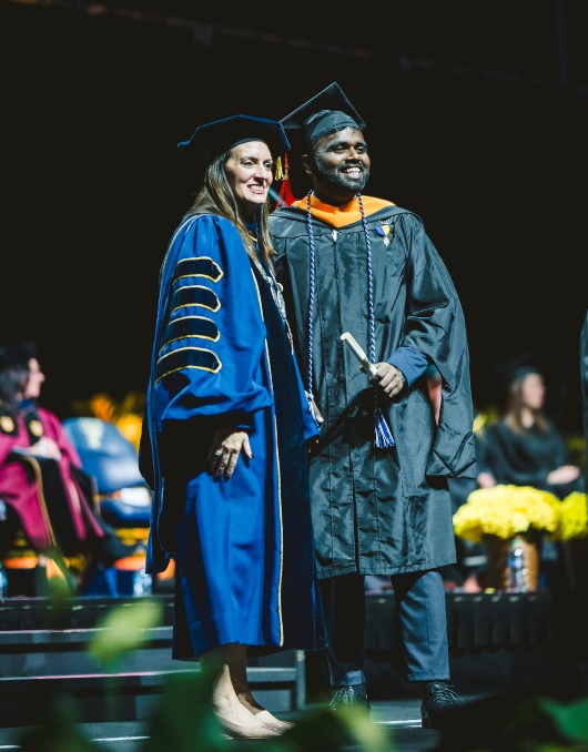 President Jeanette Nuñez poses for a photo with a graduate on stage