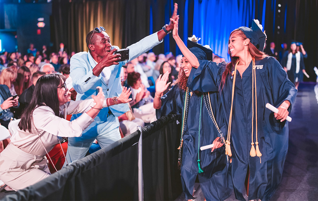 Graduates cheering with their family as they walk by