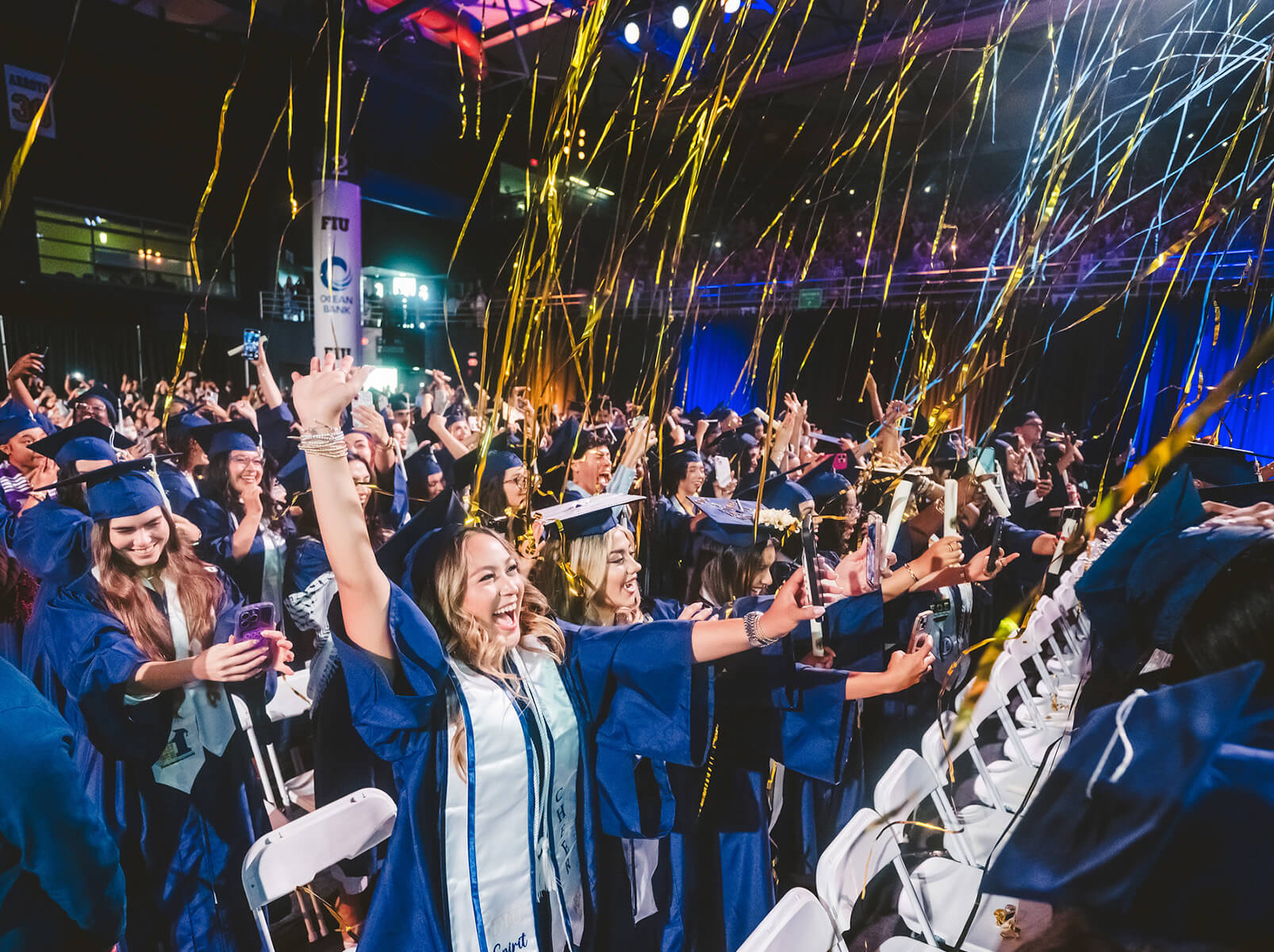Crowd of graduates cheering as confetti drops