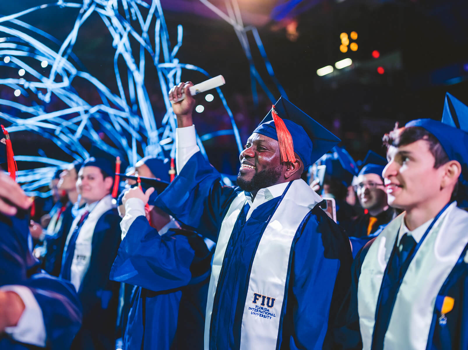 Graduate standing with fist in the air as confetti falls