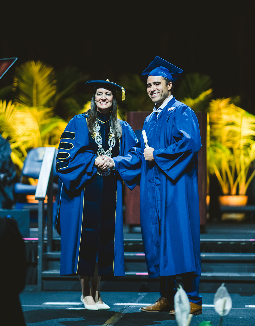 FIU Interim President Jeanette Nuñez shaking hands with graduate on stage