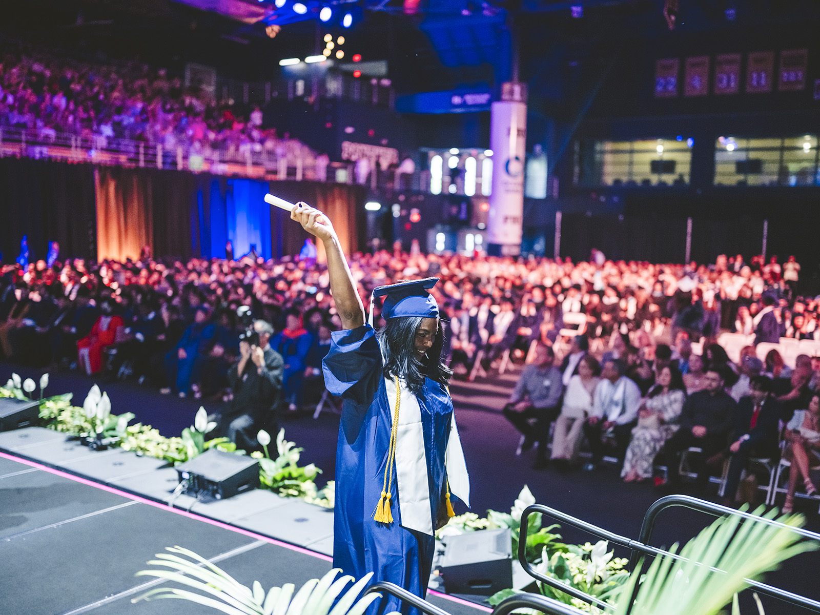 Graduate walking off stage with diploma held up high