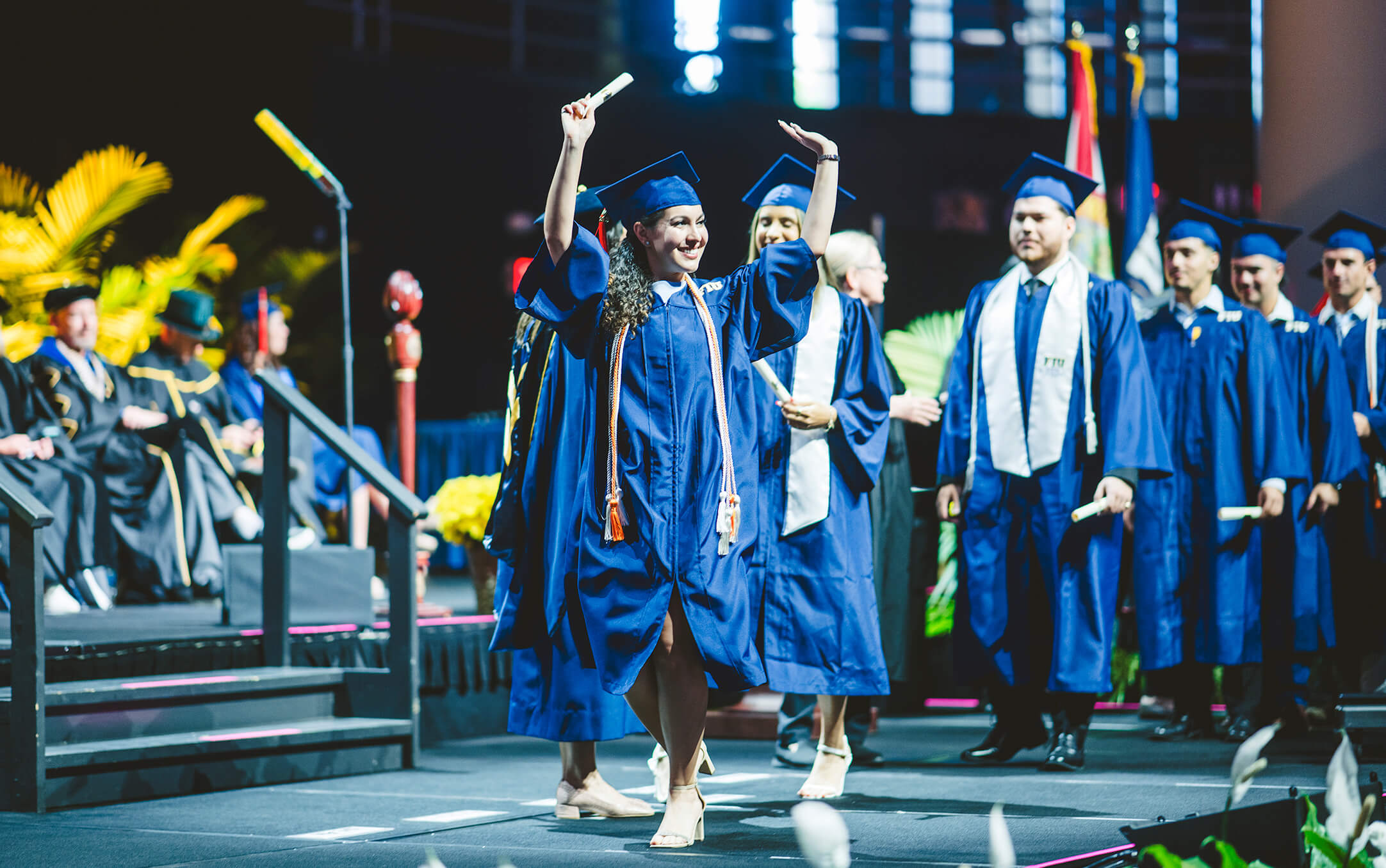 Graduate giving thumbs-up on stage