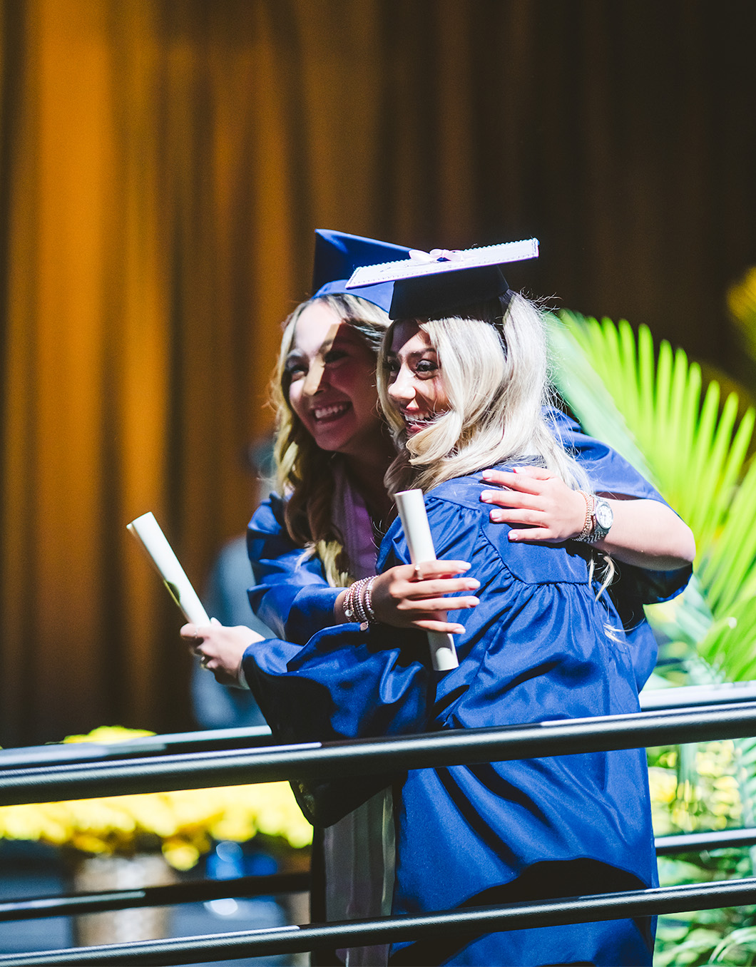 Graduates hugging as they walk off the stage