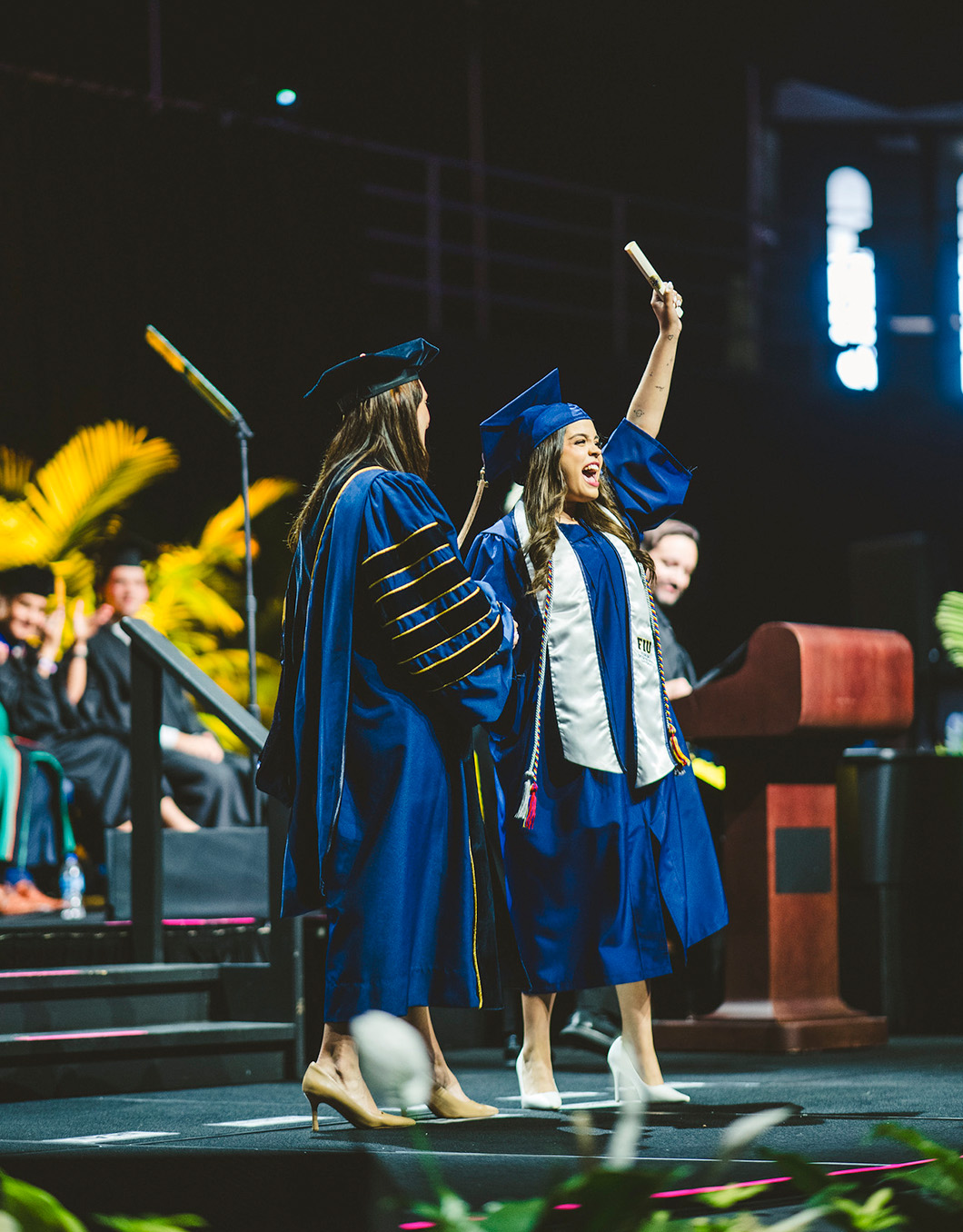 Graduate holding her diploma up in the air