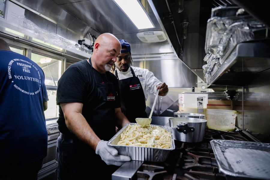 Ken Nadeau, Guy Fieri Foundation Operations Manager, and Donnell Williams, FIU Hospitality student cooking in the Foundation trailer