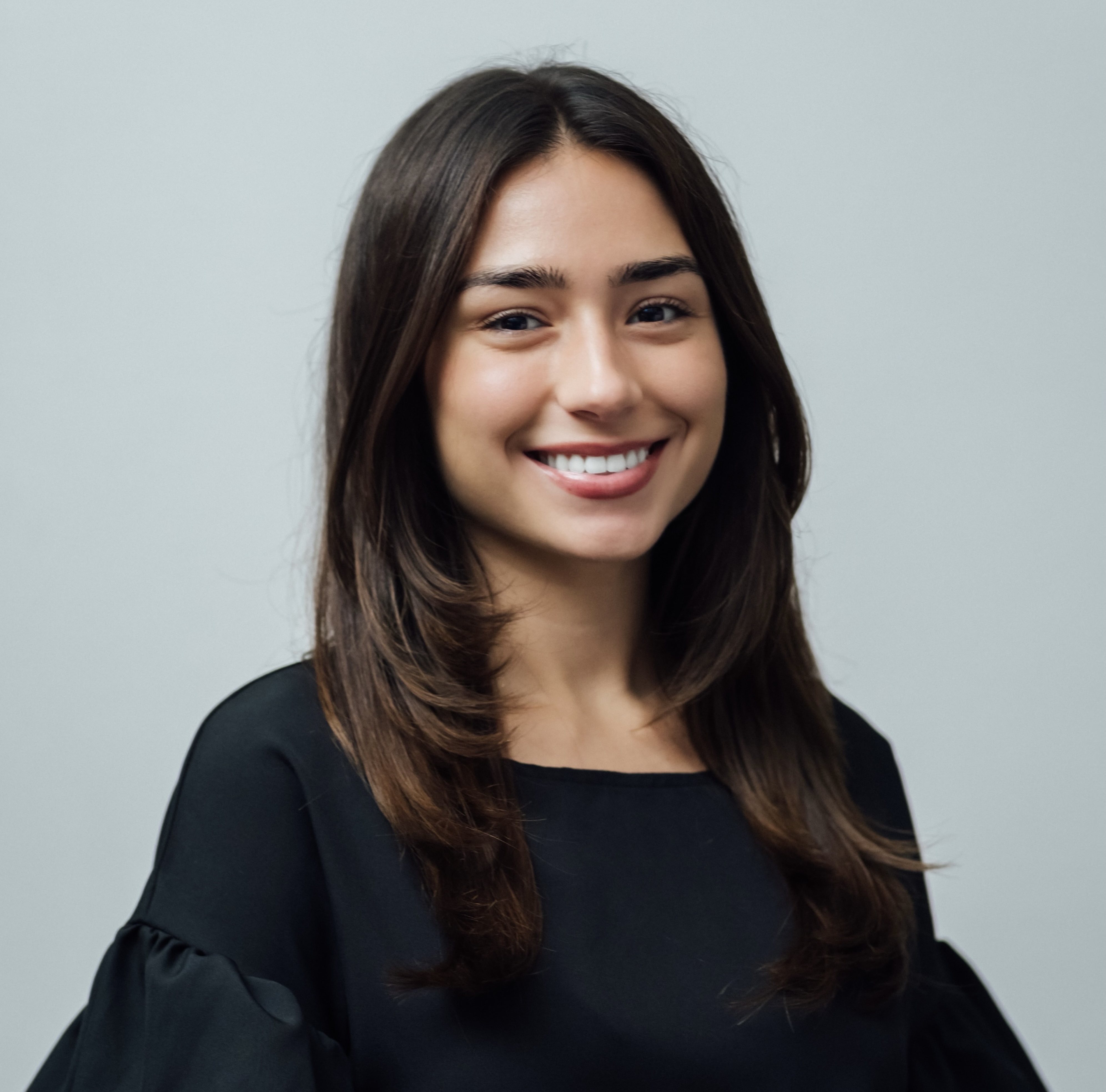 Hannah Ulloa wears a black blouse, standing facing the camera from the left.
