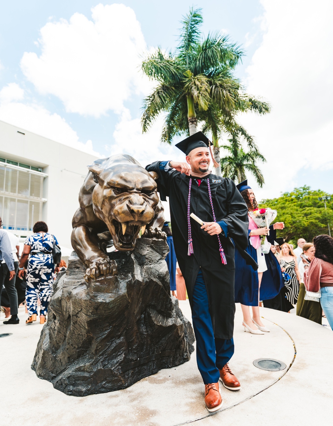 Graduate celebrating next to Panther statue