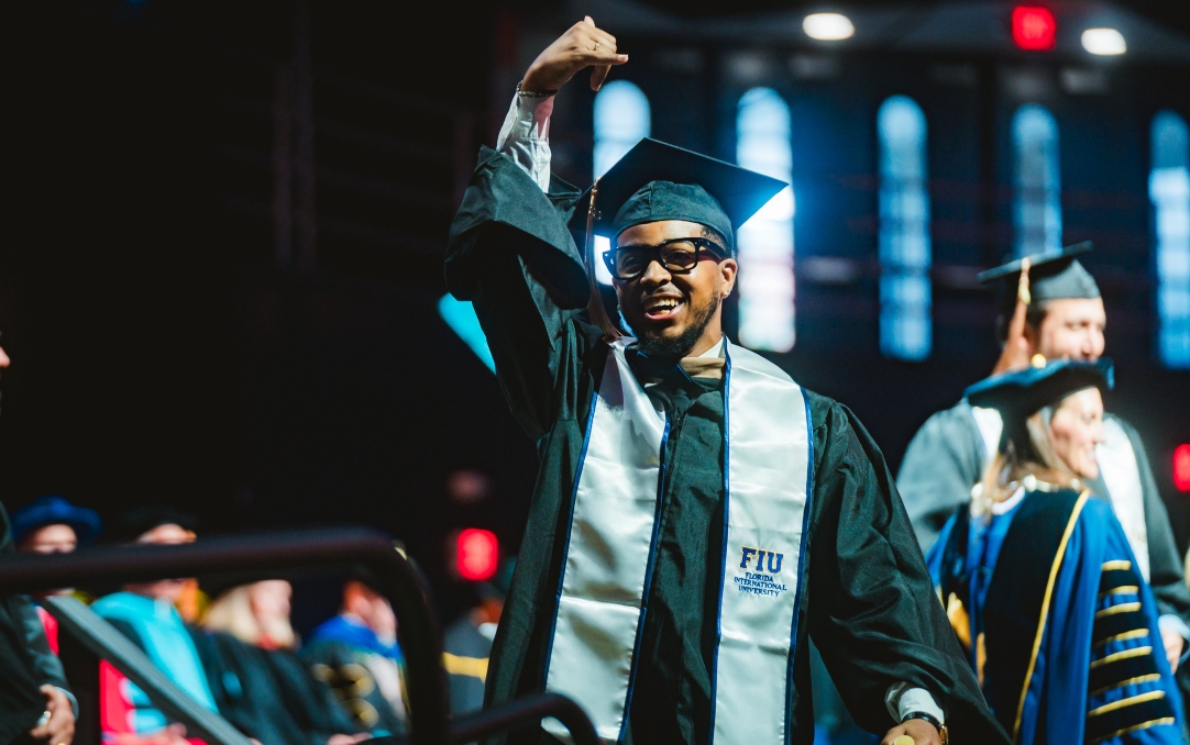 Graduate celebrating as he walks across the commencement stage