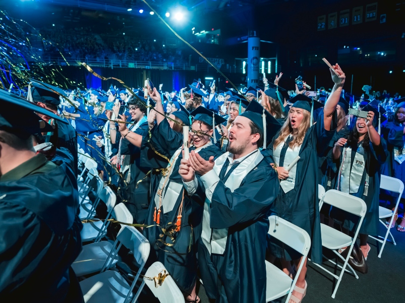 Crowd of graduates cheering as confetti drops