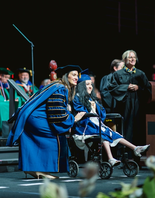 President Jeanette Nuñez poses for a photo with a graduate on stage