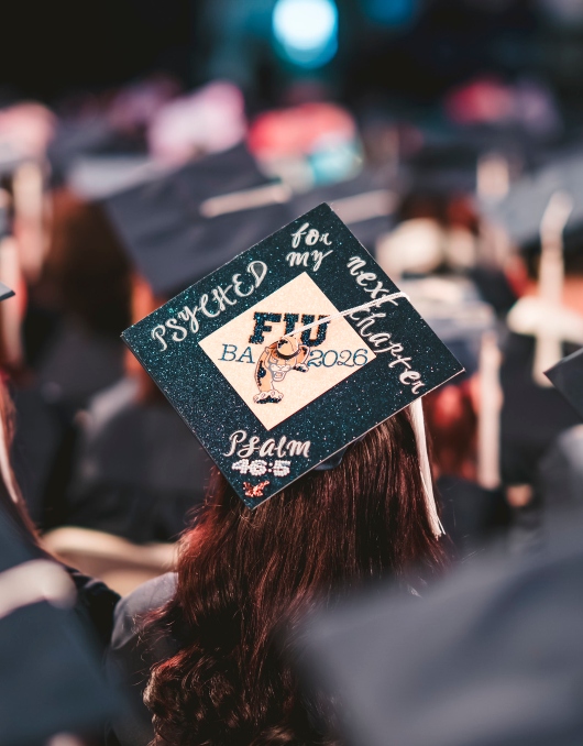 Graduate wearing a celebratory cap that says "Psyched for my next chapter. Psalm 46:5"