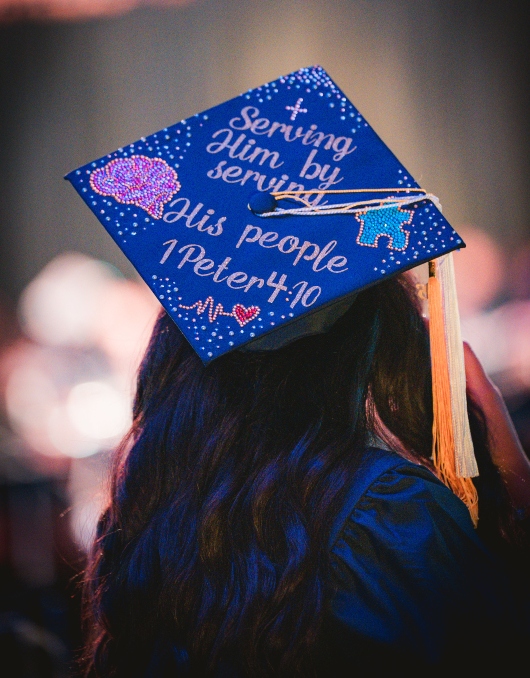 Graduate with cap that says: "Serving Him by serving His people" 1 Peter 4:10