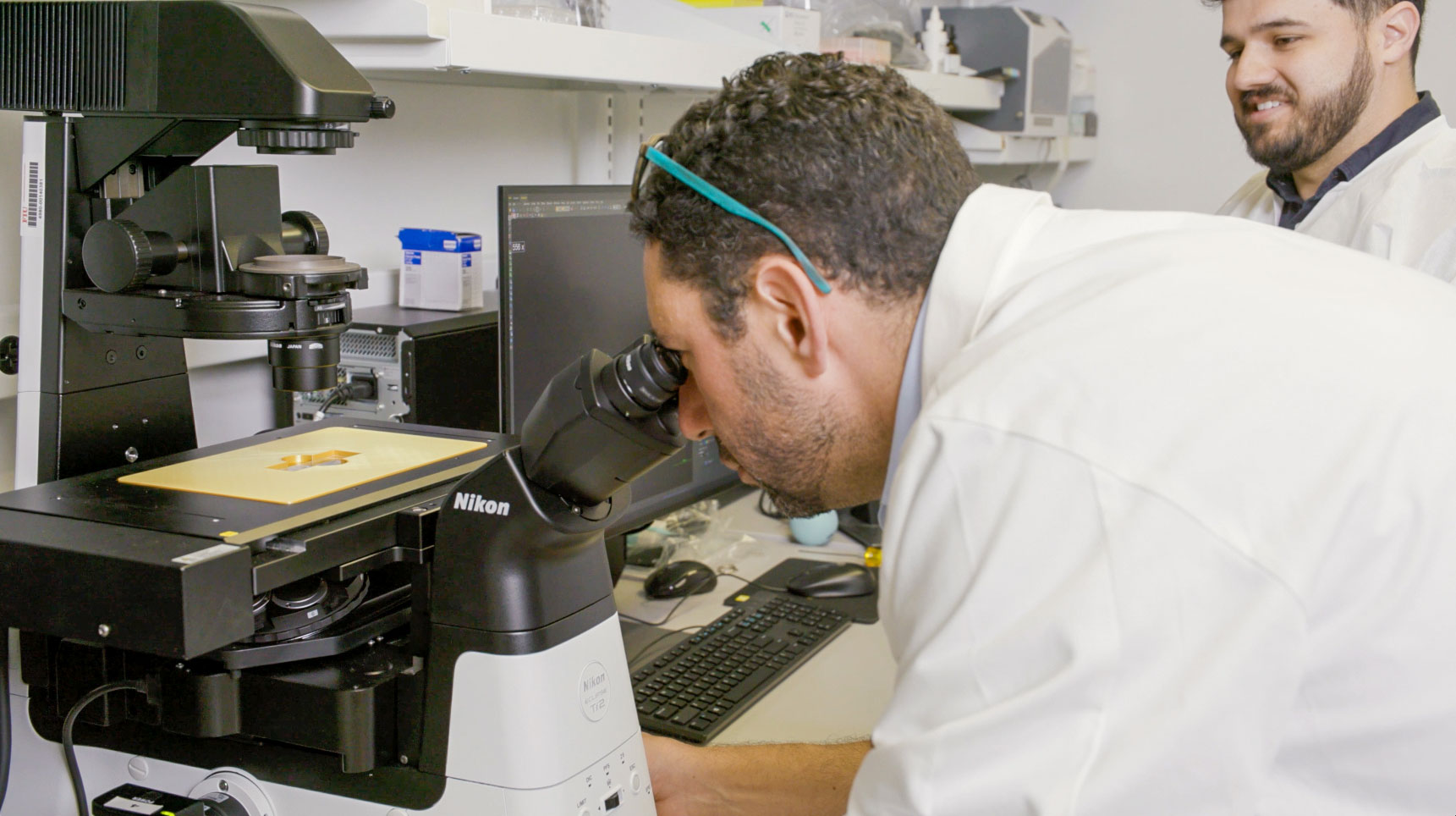 Dr. Kalfa looking through a microscope in his congenital heart research lab at FIU.
