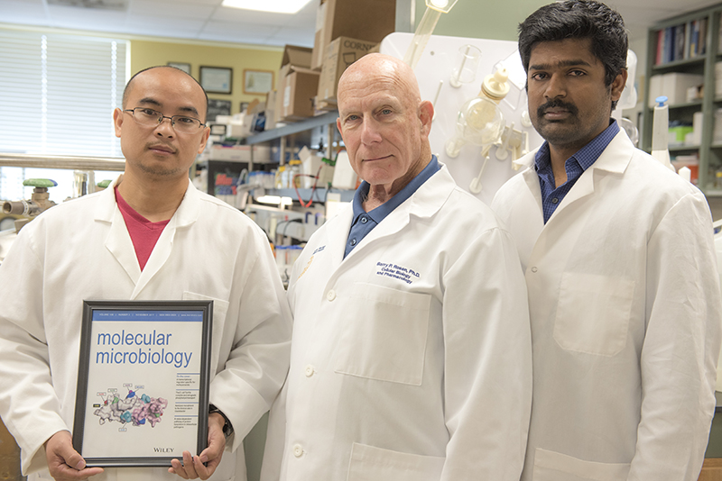 HWCOM researchers Jian Chen, Barry Rosen, and Venkadesh Nadar pose with journal cover featuring their study.